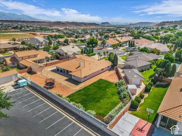 Extensive property featuring a large green lawn, a detached garage, and a long privacy wall, all set against a backdrop of distant mountains