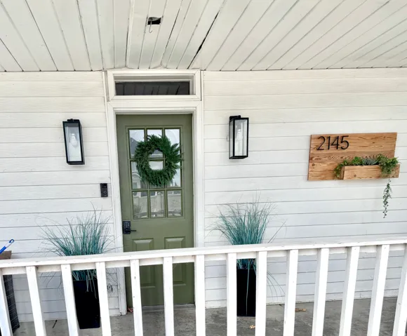 Front entry featuring a paneled door with glass inserts, a transom window, and white siding