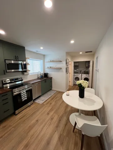 Kitchenette featuring matte green cabinetry, stainless steel appliances, wood-finish countertops, and recessed lighting