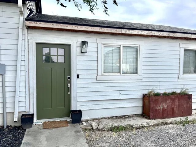 White horizontal siding exterior with a contrasting olive green entry door featuring divided lites