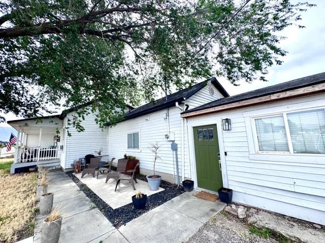 Side exterior with white horizontal siding and a prominent green entry door