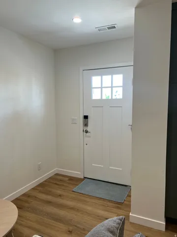 Entryway featuring a white paneled door with glass inserts, wood-finish flooring, white baseboards, and a recessed ceiling light
