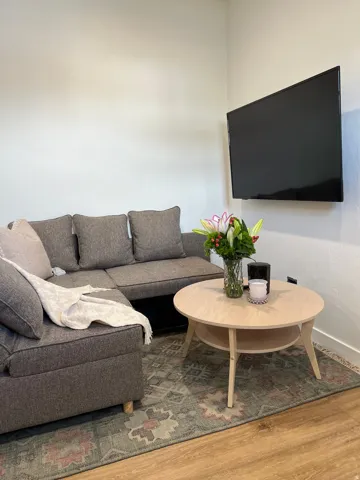 Wood-finish flooring anchors this living space, featuring a mounted television and a light-toned circular coffee table