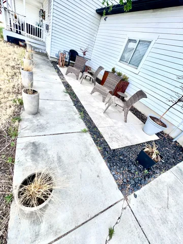 Concrete patio area featuring a white siding exterior and black river rock accents