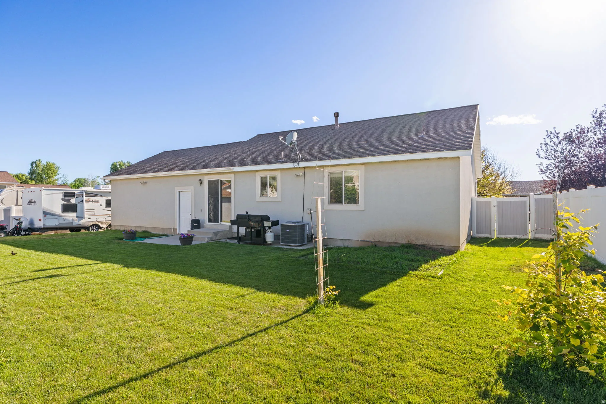 Expansive green lawn with a gray stucco exterior and dark shingle roof