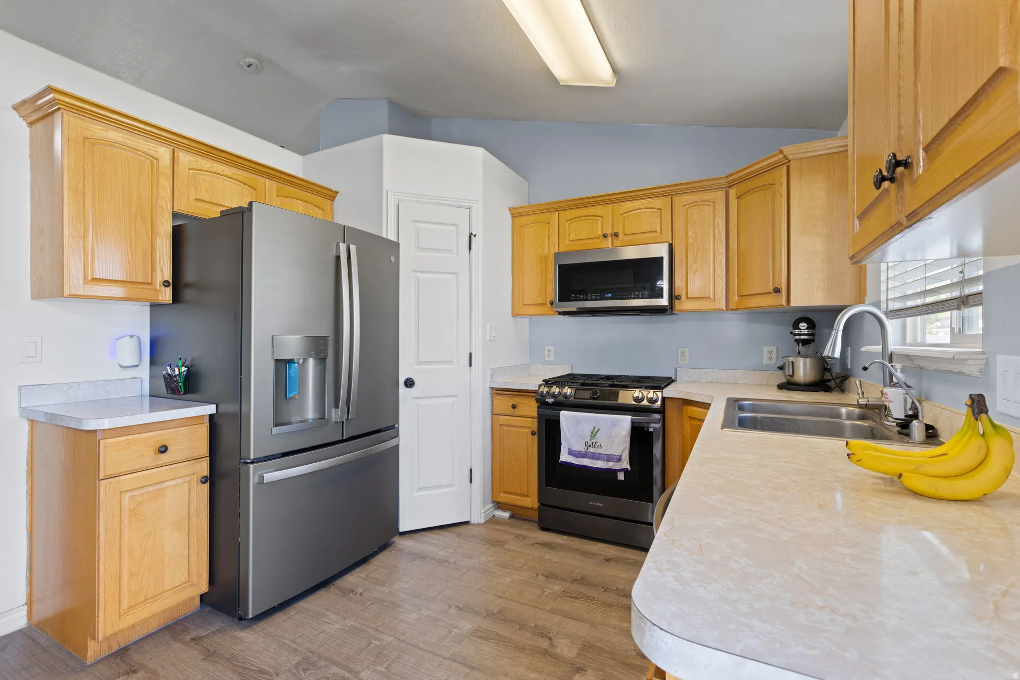 Kitchen featuring wood-finish cabinetry, stainless steel appliances, and wood-finish flooring