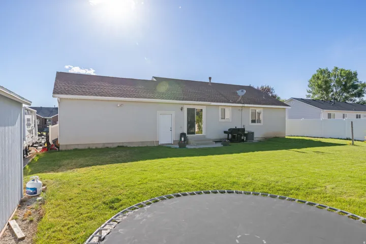 Expansive backyard featuring a manicured lawn, a concrete patio, and a white vinyl privacy fence