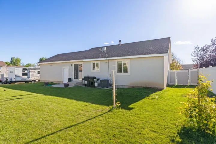 Expansive green lawn with a gray stucco exterior and dark shingle roof