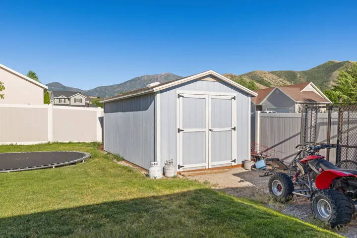 Detached storage shed featuring double barn-style doors, a sloped roof, and light blue siding