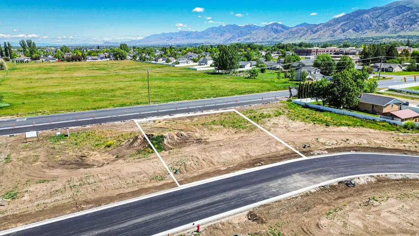 Cleared land parcel with defined boundaries, featuring new asphalt road frontage
