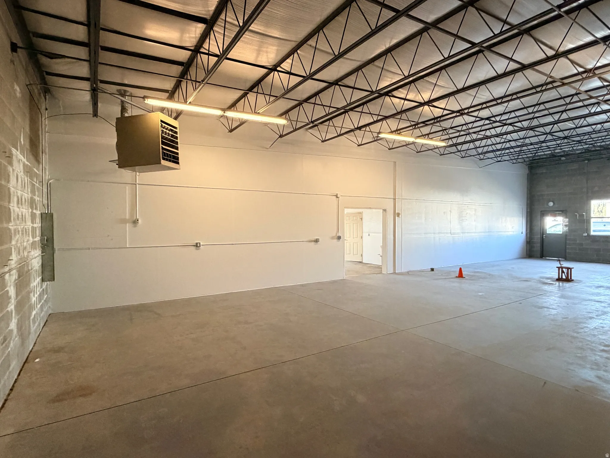 Expansive open industrial space featuring a concrete floor and exposed metal truss ceiling