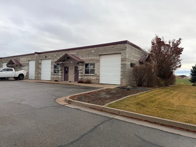Commercial building featuring block construction with multiple drive-in bays, individual entry doors, and covered entrances