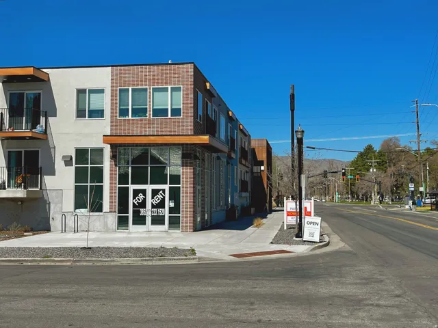 Modern mixed-use building featuring extensive storefront windows and brick facade accents