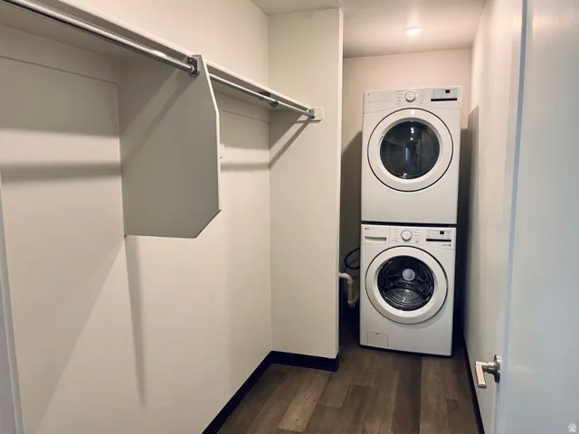 Laundry area featuring stacked appliances, wood-finish flooring, recessed lighting, and shelving with hanging rods