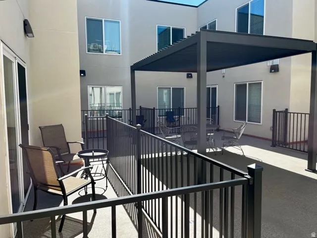 Private patio featuring a sliding glass door, black metal railing, and a modern pergola structure