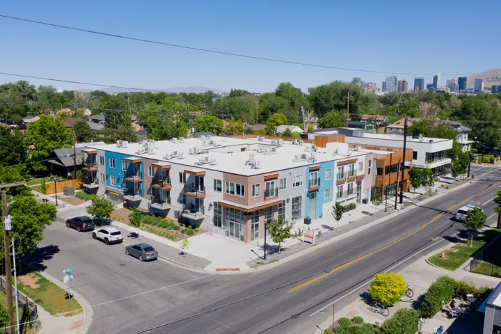 Modern multi-story building featuring varied exterior finishes including wood paneling, brick, and painted siding