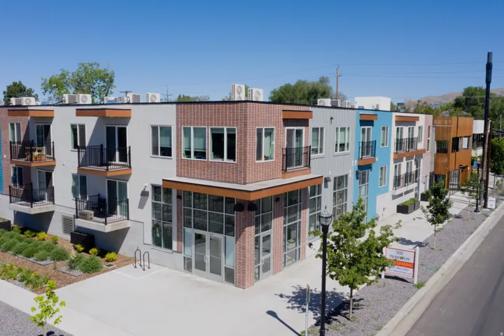 Contemporary multi-story building featuring varied facade materials including brick, vertical siding, and smooth stucco panels