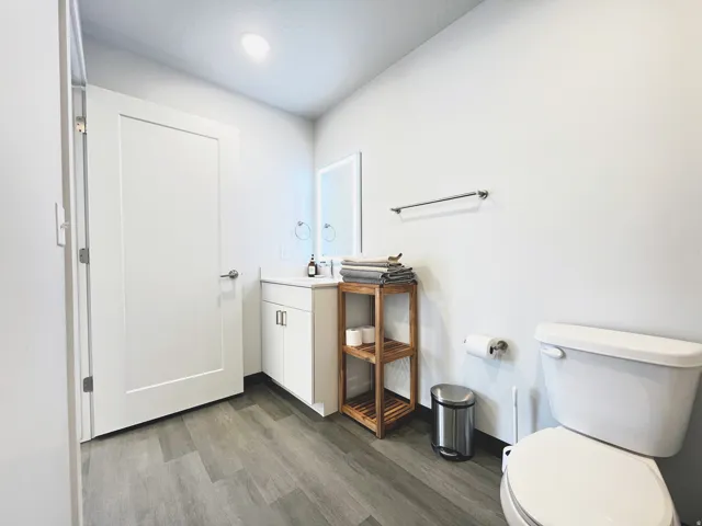 Bathroom featuring a white vanity with an undermount sink, a large wall mirror, and wood-finish flooring