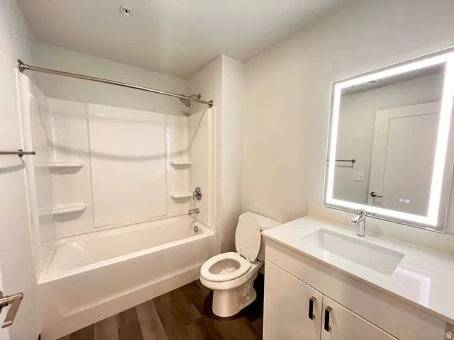 Bathroom featuring a white vanity with integrated sink, chrome faucet, and an illuminated mirror