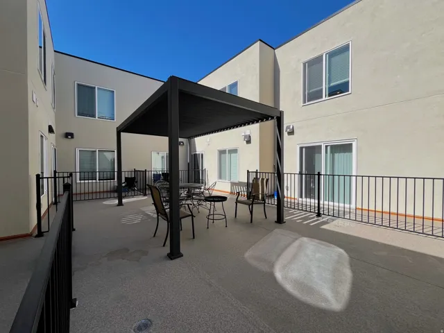 Spacious outdoor patio featuring a modern black pergola, durable concrete flooring, and perimeter railings