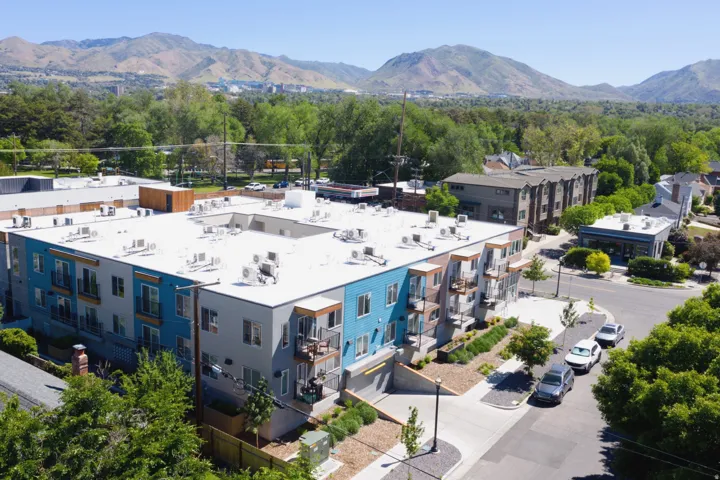 Modern multi-story building featuring varied exterior siding, private balconies, and a flat roofline