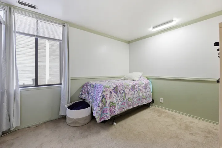 Carpeted room featuring a large window with blinds, two-tone painted walls with chair rail trim, and a ceiling-mounted light fixture