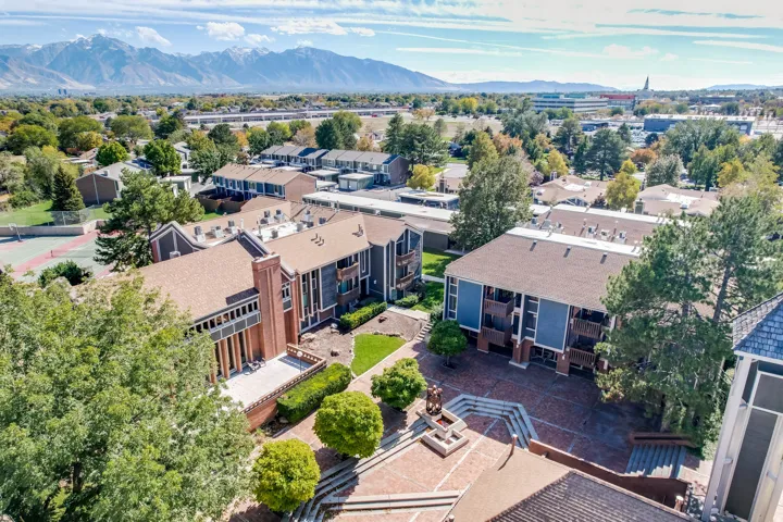 Expansive property featuring multiple multi-story residential buildings with pitched roofs, surrounded by mature trees and manicured green spaces