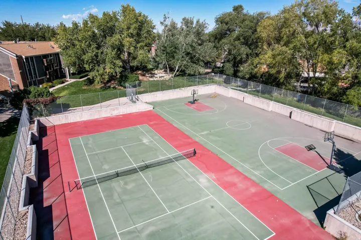 Recreational court area featuring a green and red tennis court with a net, alongside two green and red basketball courts with hoops