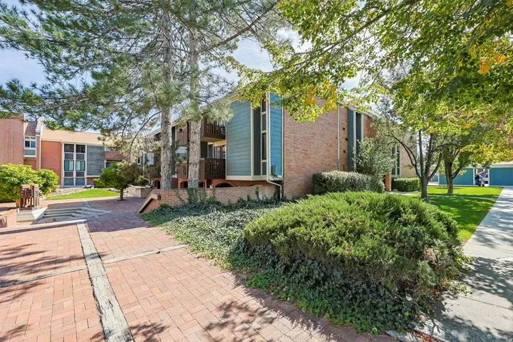Brick exterior with blue siding accents, featuring private balconies and mature landscaping