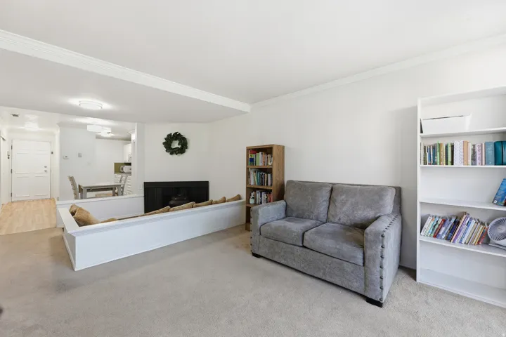 Carpeted living area featuring a fireplace with black surround, white crown molding, and recessed lighting