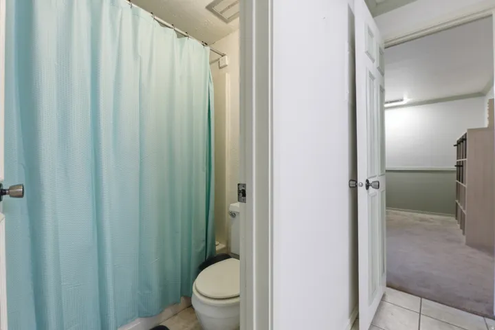 Bathroom featuring a shower-tub combination, toilet, and tiled flooring