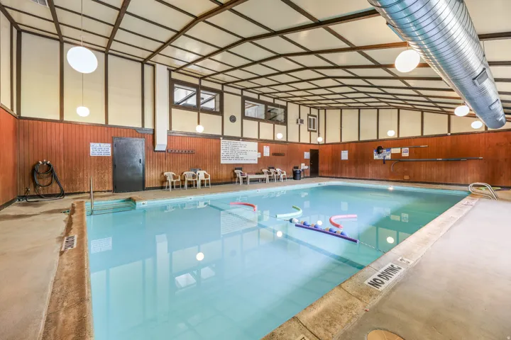 Indoor swimming pool featuring concrete decking and pool steps