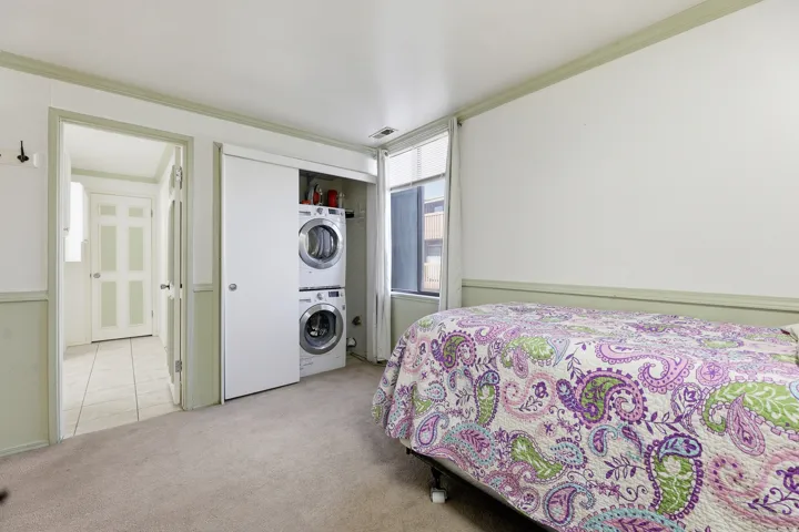 Bedroom with neutral carpeting, white and sage green two-tone walls, and a window with a white curtain