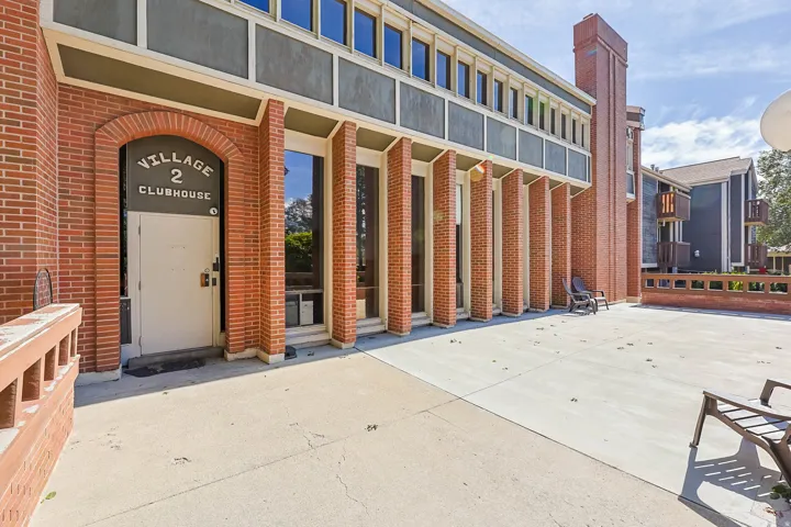 Brick facade building with a prominent arched entrance and a spacious concrete patio