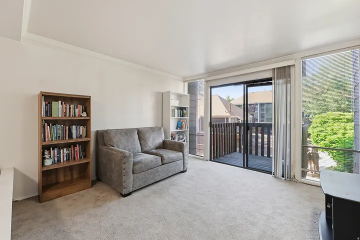 Spacious living area featuring light-colored carpeting and white wall finishes