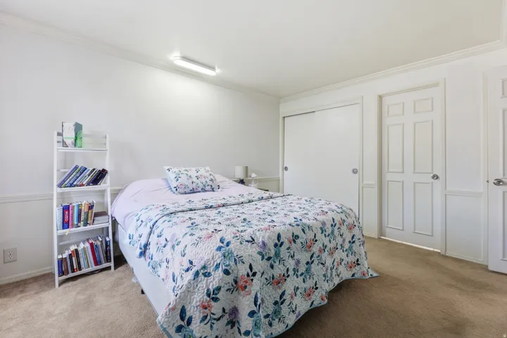 Carpeted interior room featuring white walls with wainscoting, crown molding, and a flush-mount overhead light fixture