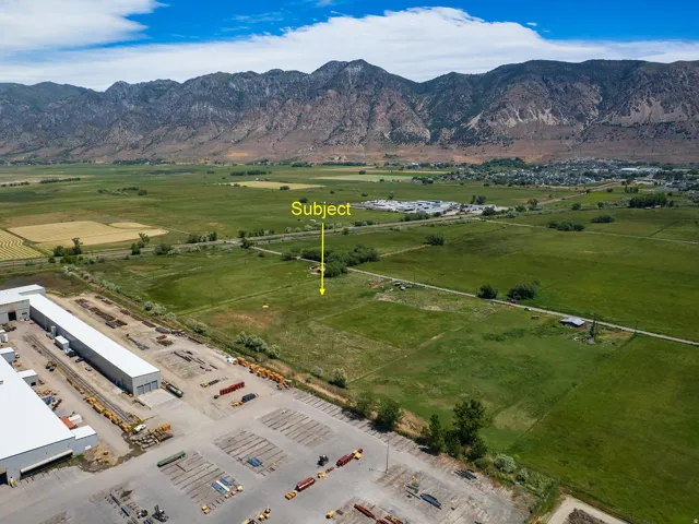 Expansive undeveloped land featuring a mountainous backdrop and proximity to industrial facilities