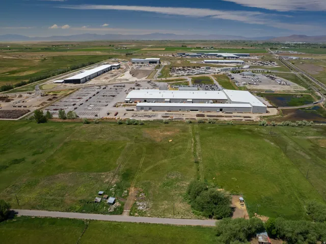 Expansive commercial property featuring multiple large industrial buildings with bright white roofs and extensive paved and unpaved outdoor storage areas
