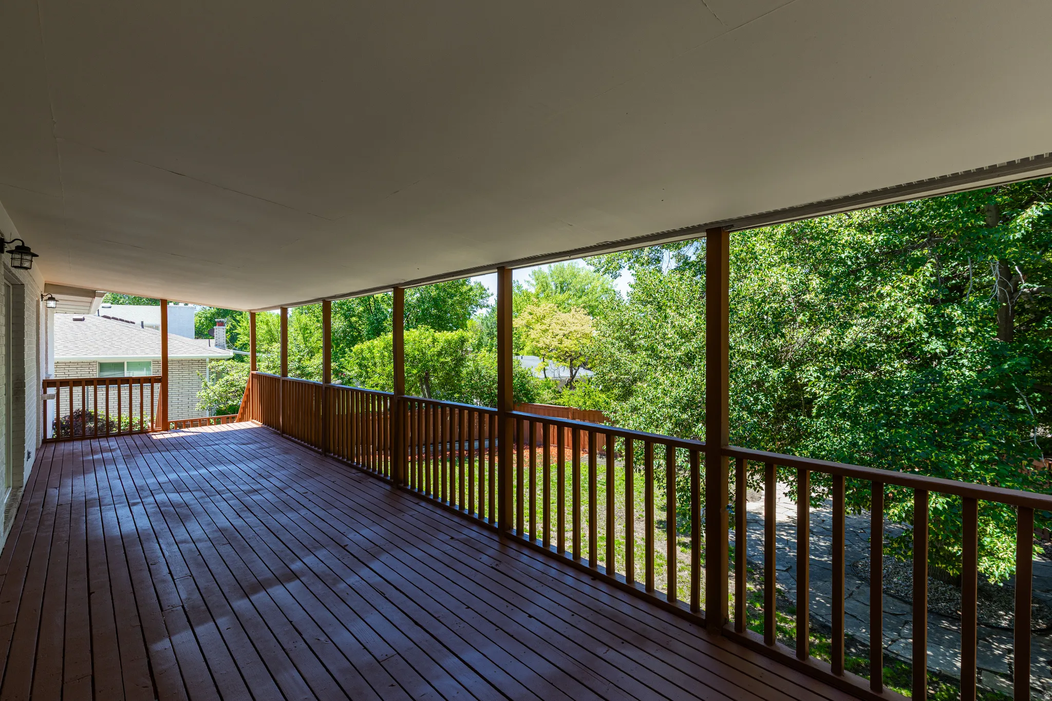 Spacious covered deck featuring wood plank flooring and a wood railing system