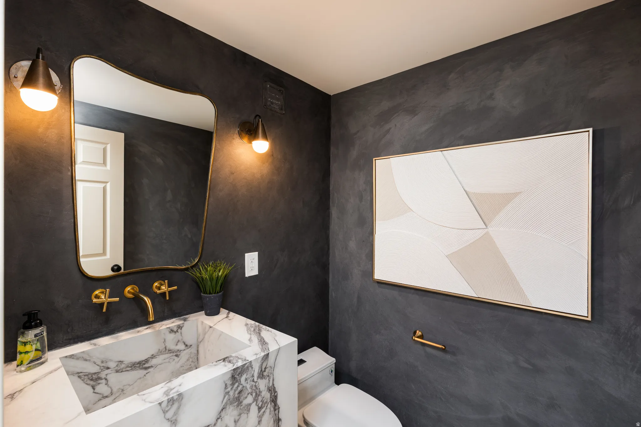 Vanity featuring a unique vessel sink with extensive veining and brass-finish wall-mounted faucet