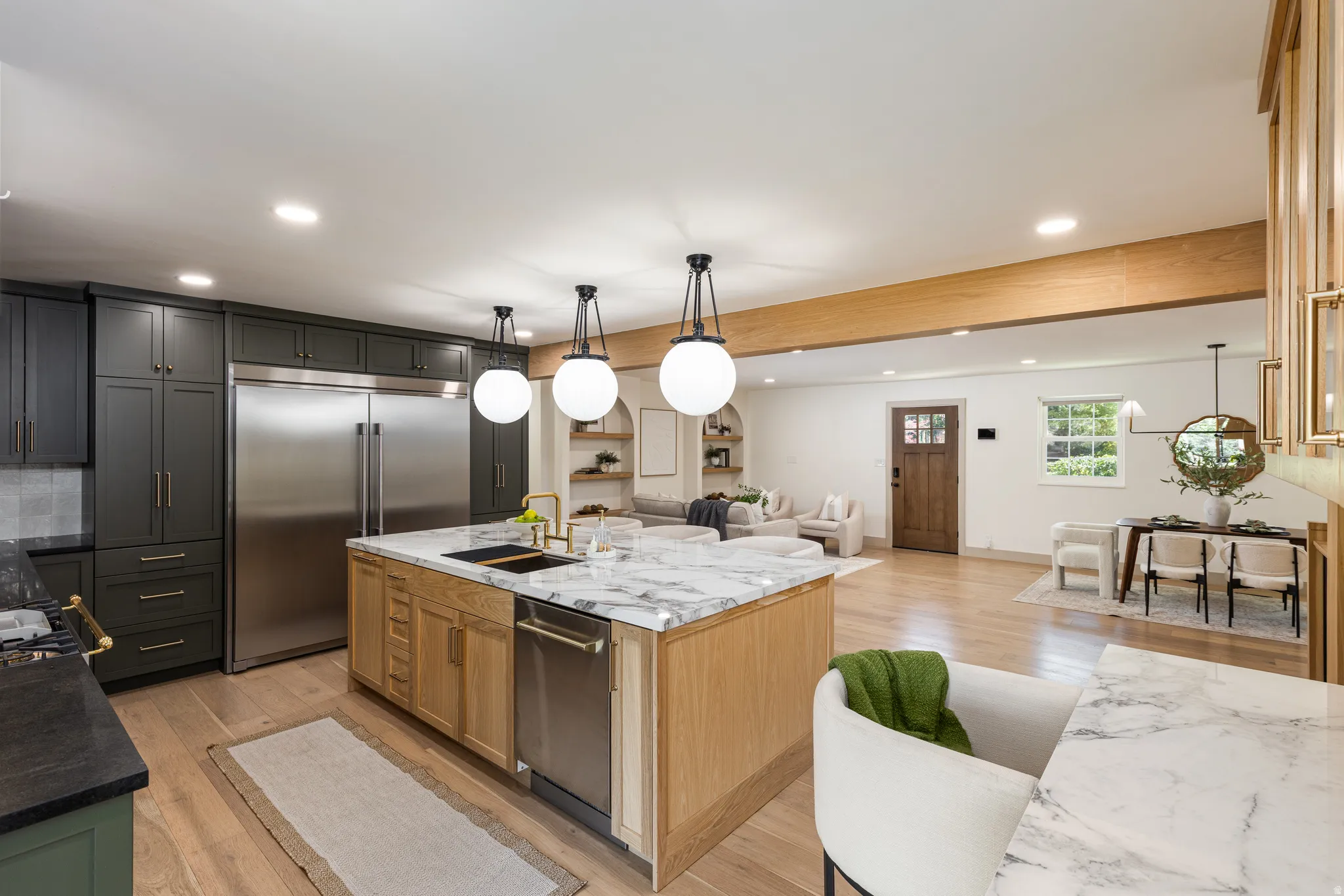 Gourmet kitchen featuring a large central island with a waterfall countertop, integrated sink, and dishwasher