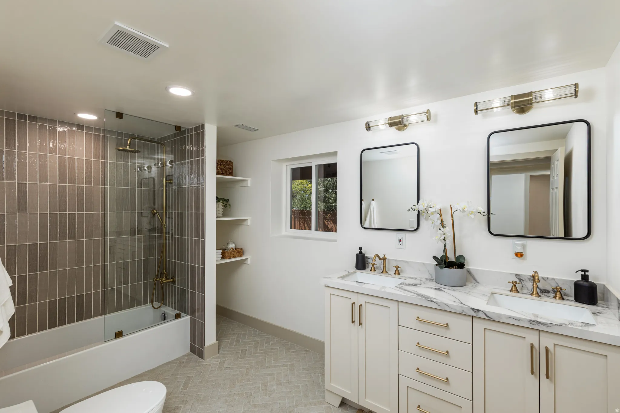Dual vanity with white cabinetry, gold-toned hardware, and a marble-patterned countertop