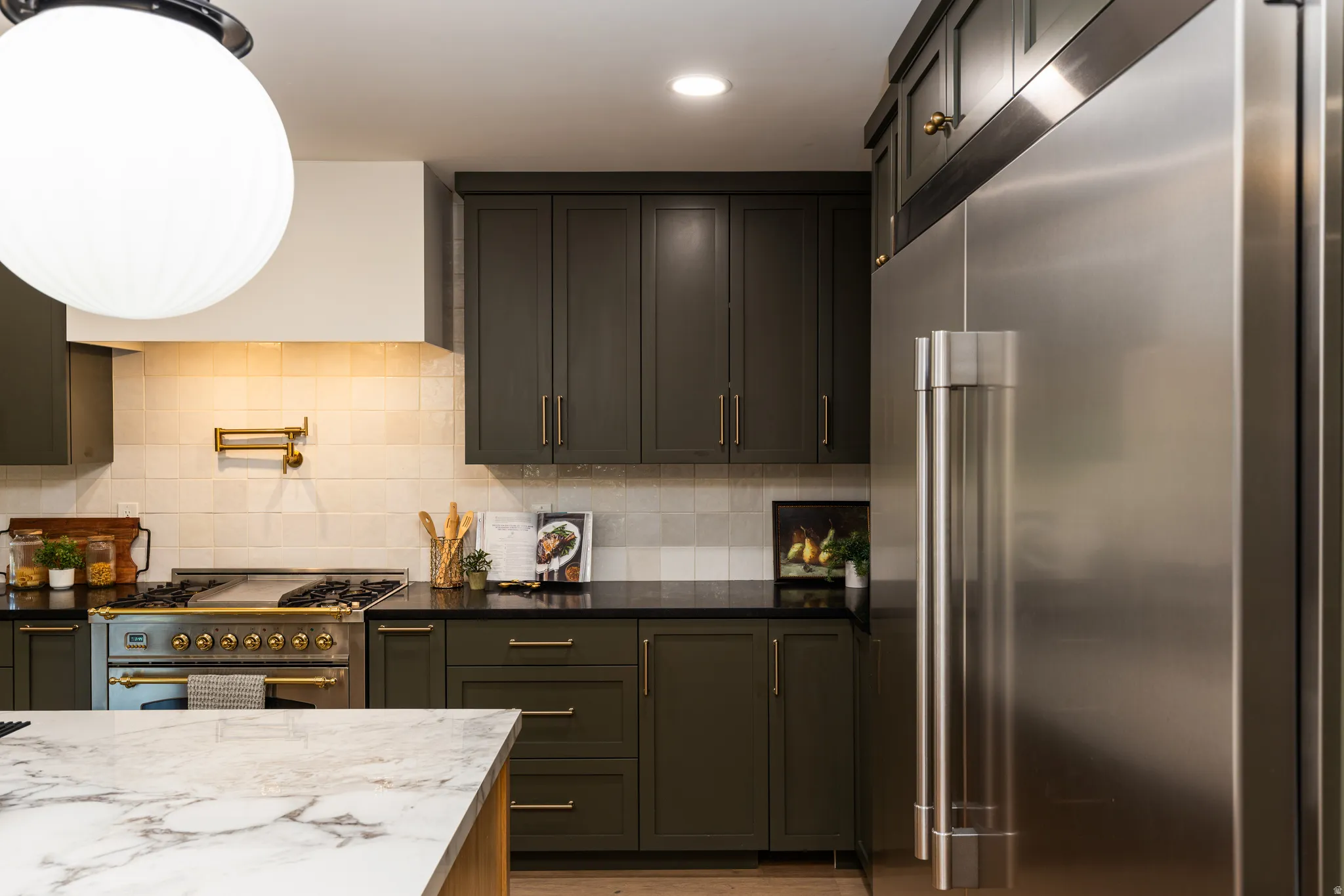 Kitchen featuring dark green cabinetry, black countertops, and a white subway tile backsplash