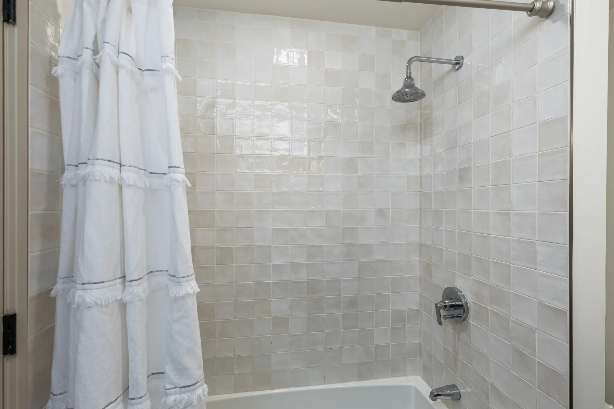 Bathtub with full-height square tile surround and chrome fixtures