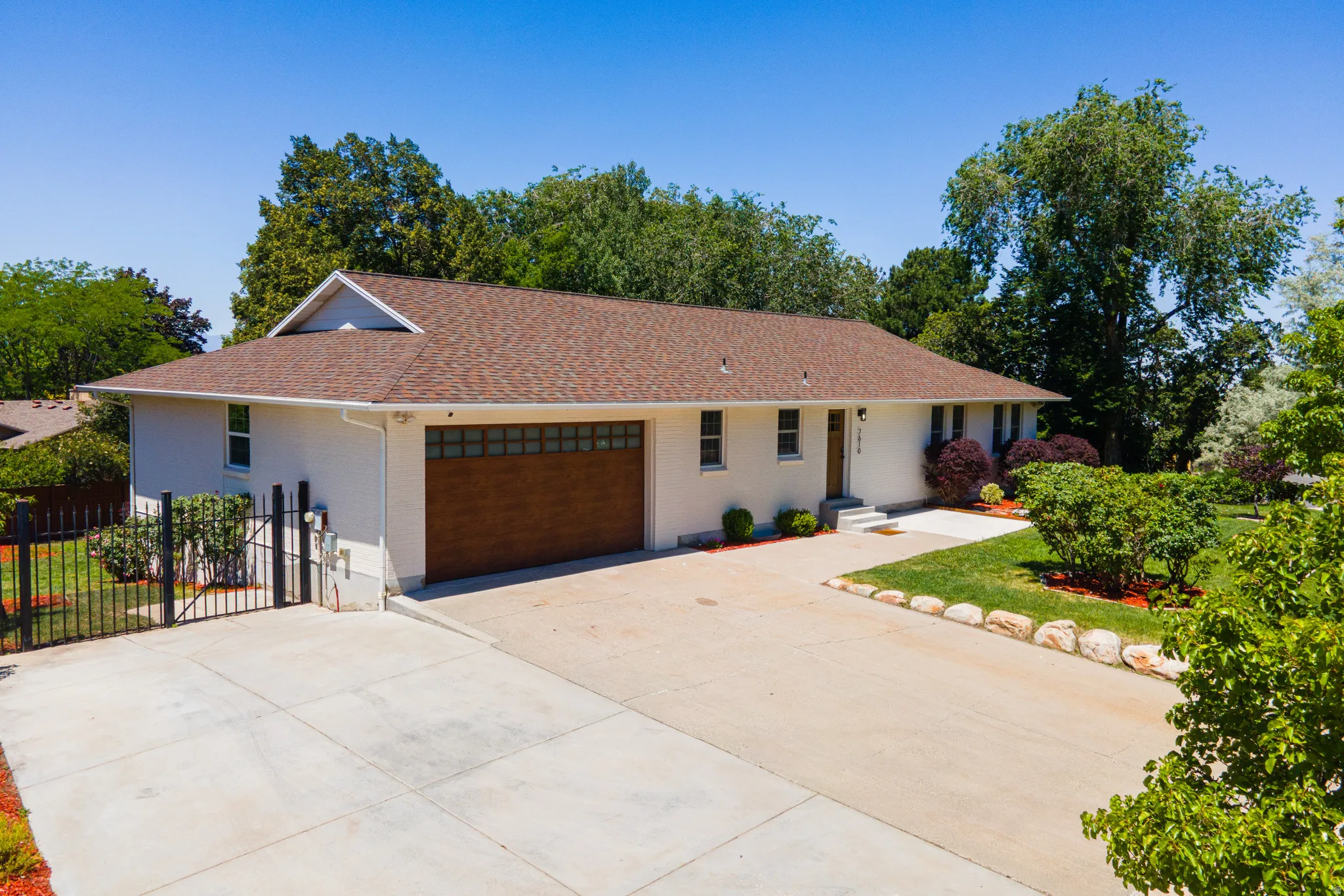 Ranch-style exterior with a brown shingle roof, attached two-car garage with wood-finish door, and concrete driveway