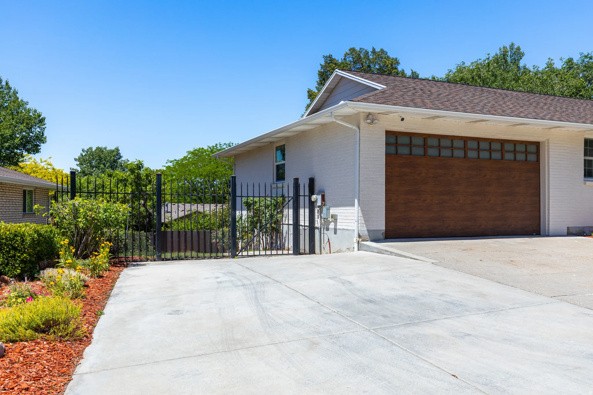 Expansive concrete driveway leading to a wood-finish garage door with upper light panels