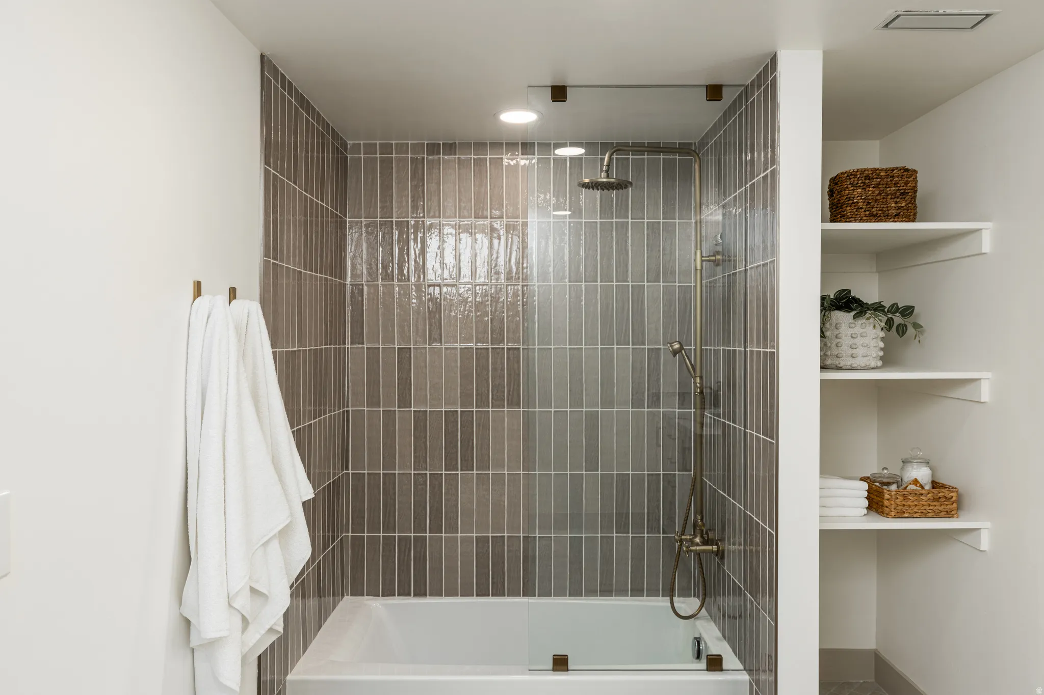 Shower-over-tub with full-height vertical tile surround, rain showerhead, and handheld spray