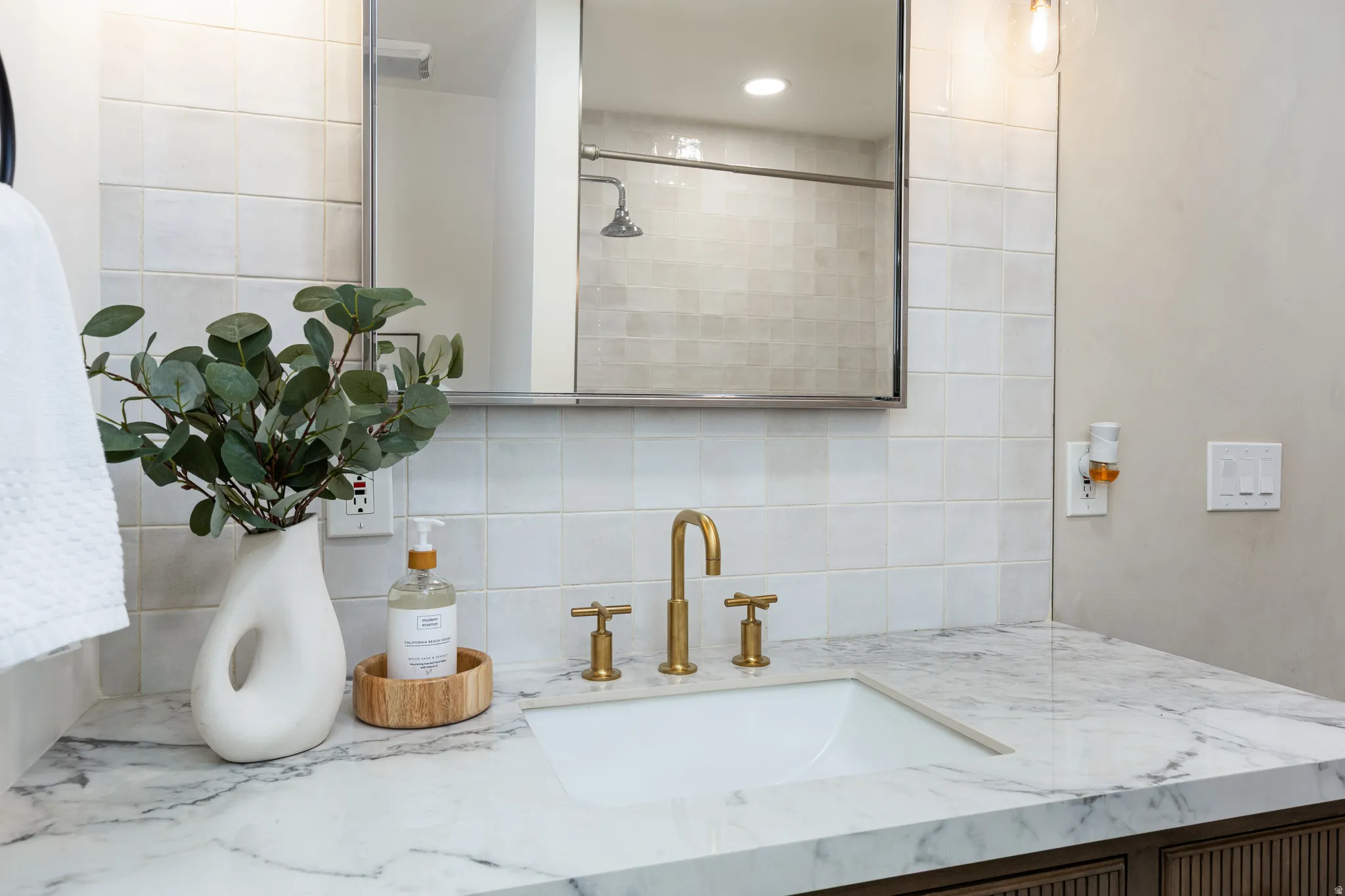 Bathroom vanity featuring a polished stone countertop, undermount sink, and brass faucet