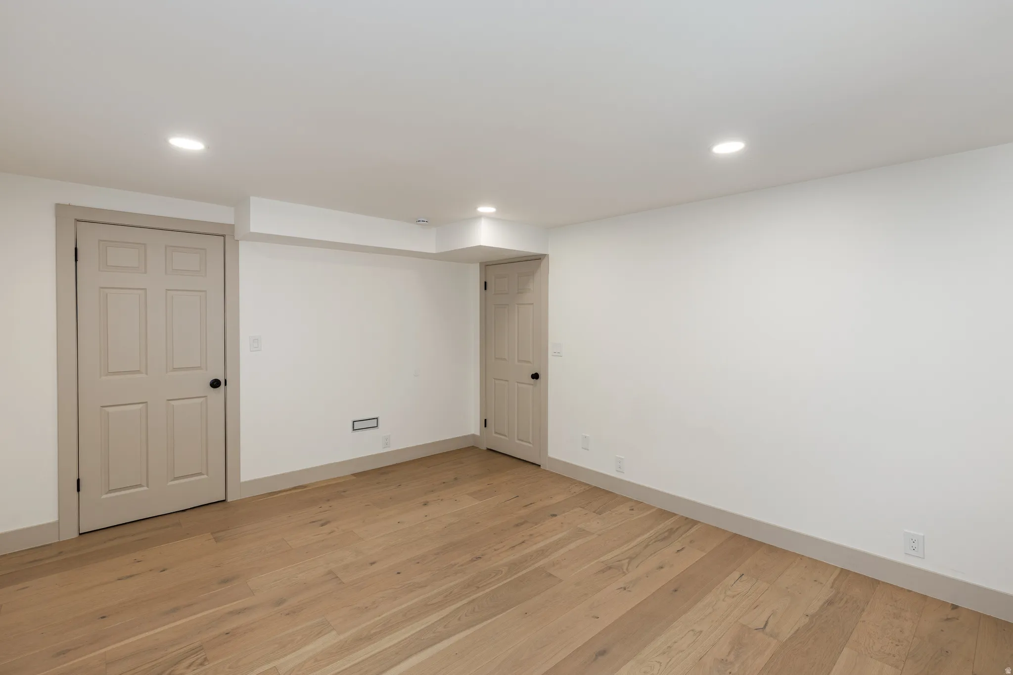 Open-concept room featuring wood-finish flooring, recessed lighting, and crisp white walls