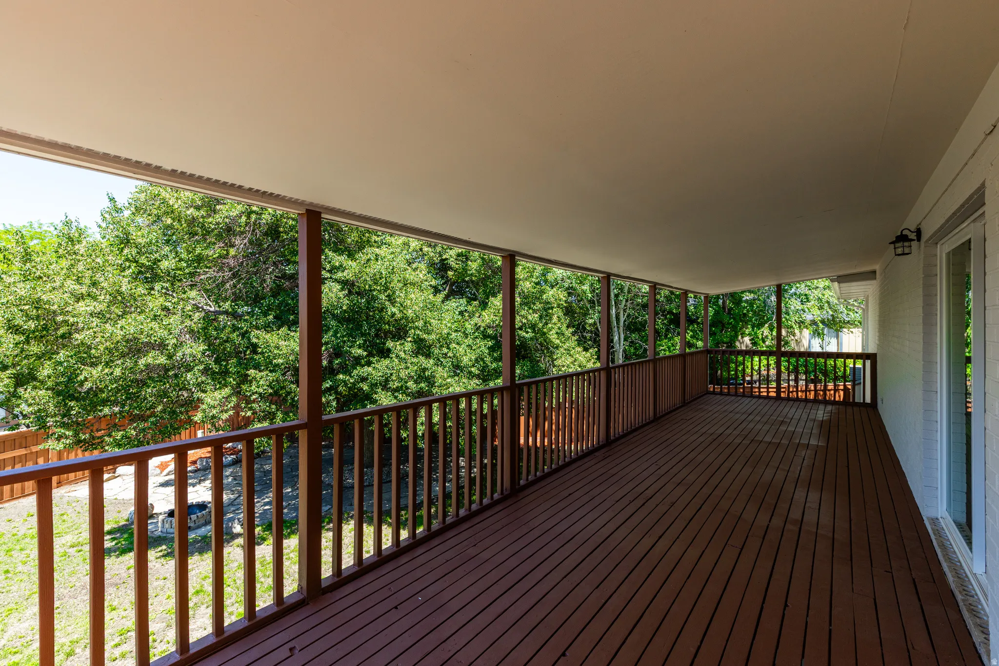 Expansive covered deck featuring wood-finish flooring, wood railings, and a solid ceiling